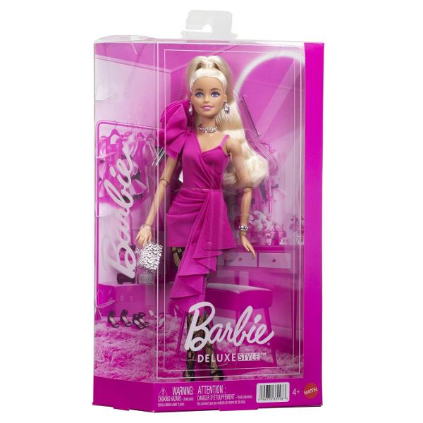 Papusa Barbie Deluxe Style impresioneaza printr-o tinuta eleganta si moderna potrivita pentru momente speciale si joaca inspirata de lumea modei Barbie poarta o rochie roz intens cu croiala asimetrica si detalii drapate completata de dresuri cu model si accesorii stralucitoare Parul blond lung coafat intr-o coada inalta completeaza look-ul sofisticat iar cerceii colierul bratara si poseta argintie adauga un plus de stil Papusa este articulata si poate fi pozitionata in diferite 