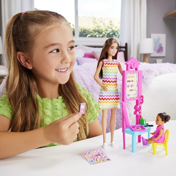 Descopera setul de joaca Barbie Profesor perfect pentru copiii care isi doresc sa exploreze lumea educatiei prin joaca Acest set ofera oportunitatea de a recrea lectii interesante si de a invata prin scenarii interactive Setul include o papusa Barbie satena profesoara imbracata intr-o rochie colorata cu model vesel gata sa predea lectii captivante Sala de clasa este echipata cu o tabla interactiva materiale educative si accesorii specifice care completeaza experienta de invatare De 