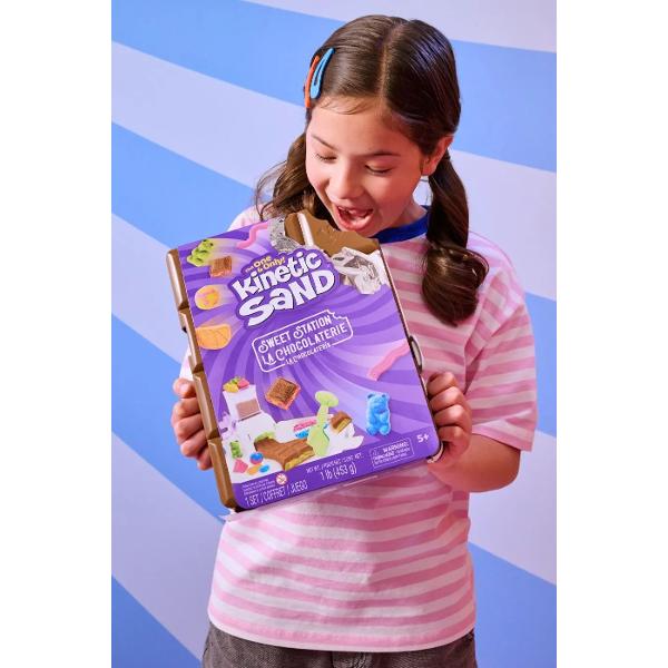 Creeaza si personalizeaza bomboane si dulciuri cu Statia de Dulciuri Kinetic Sand Acest set de joaca adorabil ii invita pe tinerii cofetari sa isi faca propriile dulciuri din nisip Cu un total de 450g de nisip roz galben turcoaz si maro copiii pot amesteca culorile pentru a modela viermisori gumati sau batoane de ciocolata Masina de bomboane face distractia si mai mare incarca nisipul roteste manivela si priveste cum apar deliciile Acest proces interactiv dezvolta abilitatile motorii 