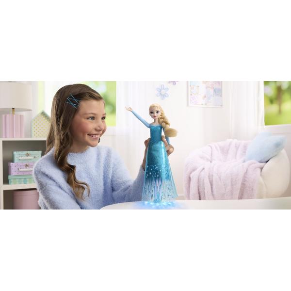 Papusa Elsa din Disney Frozen aduce magia Regatului de Gheata intr-o versiune interactiva cu muzica si efecte luminoase Prin apasarea zonei indicate pe piept papusa activeaza o melodie si lumini care pun in valoare tinuta inspirata de personajul Elsa Papusa poarta o rochie eleganta in nuante de albastru cu detalii stralucitoare si motive inspirate de gheata si fulgi de zapada Parul blond impletit lateral completeaza aspectul emblematic al personajului Este potrivita pentru recrearea 