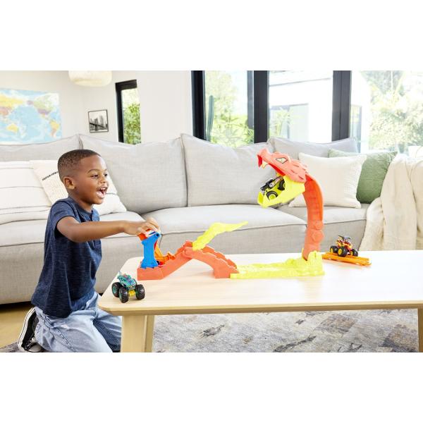 Setul de joaca Hot Wheels Monster Truck Invinge Sarpele Urias aduce spectacolul arenelor de cascadorii direct in camera copiilor Inspirat din competitiile Monster Trucks acest circuit plin de actiune provoaca jucatorii sa invinga un sarpe urias care pazeste arena Masinuta Monster Truck este lansata pe pista cu viteza pentru a sari peste obstacole si pentru a lovi tinta incercand sa doboare capul sarpelui gigantic Mecanismul interactiv transforma fiecare lansare intr-o provocare 
