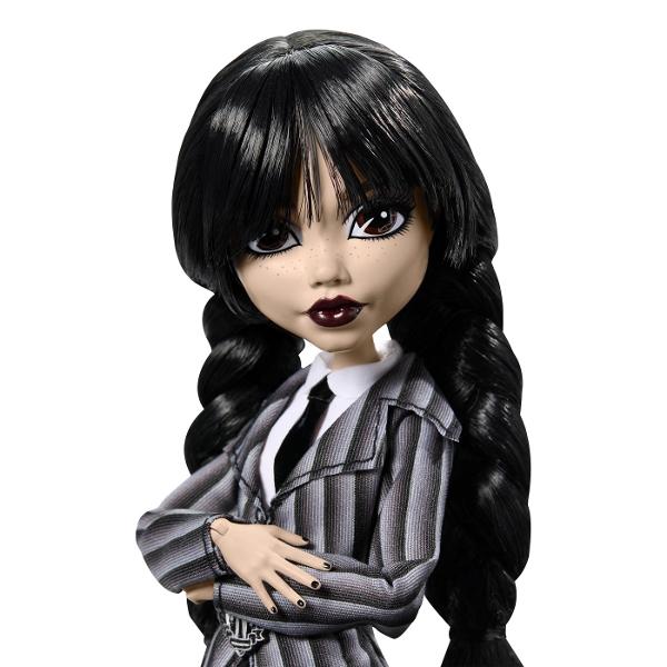 Papusa Wednesday este un must-have pentru fanii seriei Monster High imbinand stilul intunecat cu detalii elaborate care transforma aceasta papusa intr-o piesa de colectie deosebita Papusa poarta uniforma Academiei Nevermore completata de detalii unice precum cravata cureaua si ciorapii cu imprimeu de paianjen care subliniaza estetica ei sumbra si eleganta Cizmele papusii sunt decorate cu elemente inspirate din universul Wednesday Pe un toc este sculptat violoncelul ei iar pe celalalt 