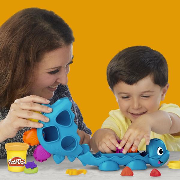 Acest set de joaca creativ ii ajuta pe cei mici sa invete formele si culorile intr-un mod distractiv Dinozaurul prietenos are spatii speciale pentru diferite forme iar copiii pot folosi plastilina colorata pentru a le modela si potrivi Setul include 6 recipiente de Play Doh in culori variate si accesorii pentru joaca interactiva Potrivit pentru copiii de la 2 ani in sus acest set stimuleaza imaginatia abilitatile motorii fine si invatarea prin joaca transformand fiecare activitate intr-o 