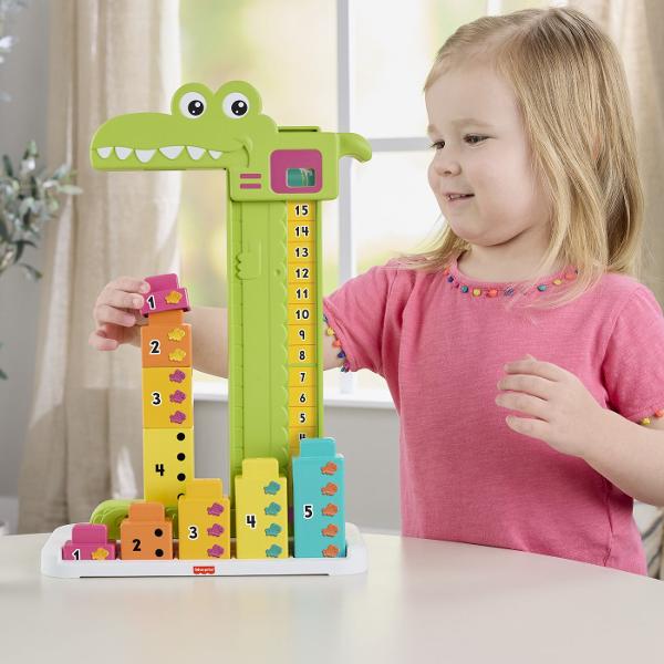 Jucaria educativa Fisher-Price Stivuibila Alligator ii ajuta pe copii sa invete concepte matematice de baza prin joc si interactiune Designul colorat in forma de crocodil transforma invatarea numerelor si a adunarilor simple intr-o activitate distractiva Setul include blocuri numerotate si un mecanism glisant care permite copiilor sa combine numerele si sa descopere rezultatul pe scala de calcul Prin manipularea pieilor si rezolvarea provocarilor simple copiii isi dezvolta gandirea logica 