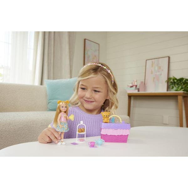 Setul Barbie Family and Friends Clubul lui Chelsea Petrecere Cu Ceai Surpriza transforma timpul de joaca intr-o petrecere vesela in aer liber Setul include o papusa Chelsea si multe accesorii tematice pentru un picnic sau o petrecere cu ceai precum cani ceainic deserturi si alte elemente decorative Standul de servire se poate transforma intr-un cos de picnic compact usor de transport si depozitat Culorile vesele si detaliile inspirate din lumea deserturilor creeaza o atmosfera jucausa 