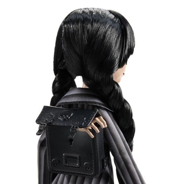 Papusa Wednesday este un must-have pentru fanii seriei Monster High imbinand stilul intunecat cu detalii elaborate care transforma aceasta papusa intr-o piesa de colectie deosebita Papusa poarta uniforma Academiei Nevermore completata de detalii unice precum cravata cureaua si ciorapii cu imprimeu de paianjen care subliniaza estetica ei sumbra si eleganta Cizmele papusii sunt decorate cu elemente inspirate din universul Wednesday Pe un toc este sculptat violoncelul ei iar pe celalalt 