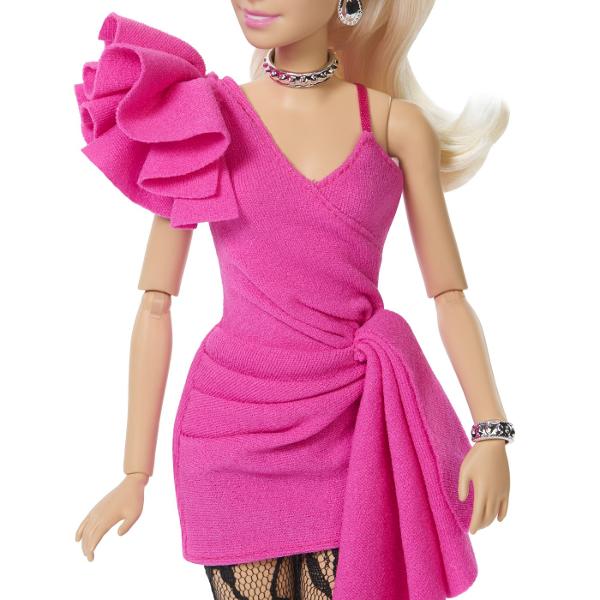 Papusa Barbie Deluxe Style impresioneaza printr-o tinuta eleganta si moderna potrivita pentru momente speciale si joaca inspirata de lumea modei Barbie poarta o rochie roz intens cu croiala asimetrica si detalii drapate completata de dresuri cu model si accesorii stralucitoare Parul blond lung coafat intr-o coada inalta completeaza look-ul sofisticat iar cerceii colierul bratara si poseta argintie adauga un plus de stil Papusa este articulata si poate fi pozitionata in diferite 