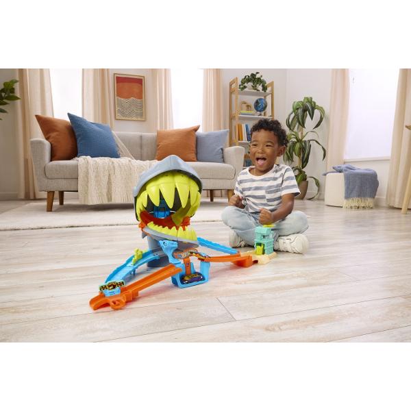 Setul de joaca Hot Wheels City Plaja Rechinului Chomp aduce actiune spectaculoasa pe pista unde masinutele trebuie sa scape din ghearele unui rechin urias Inspirat din universul Hot Wheels City acest circuit transforma plaja intr-o aventura plina de adrenalina si provocari pentru micii pasionati de curse Masinutele sunt lansate pe pista si trebuie sa treaca cu viteza prin zona periculoasa dominata de rechinul gigantic cu falci mobile Daca masina nu este suficient de rapida rechinul poate 