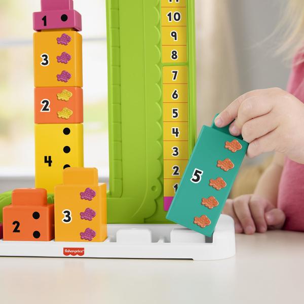 Jucaria educativa Fisher-Price Stivuibila Alligator ii ajuta pe copii sa invete concepte matematice de baza prin joc si interactiune Designul colorat in forma de crocodil transforma invatarea numerelor si a adunarilor simple intr-o activitate distractiva Setul include blocuri numerotate si un mecanism glisant care permite copiilor sa combine numerele si sa descopere rezultatul pe scala de calcul Prin manipularea pieilor si rezolvarea provocarilor simple copiii isi dezvolta gandirea logica 