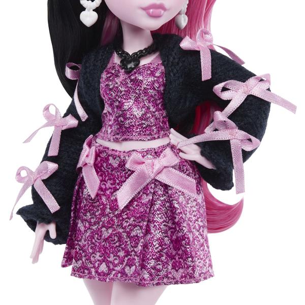 Intra in atmosfera gotica si plina de stil din universul Monster High cu papusa Draculaura un personaj emblematic cu un look adorabil si indraznet Draculaura impresioneaza prin parul lung in doua nuante contrastante si tinuta stralucitoare in tonuri de roz si negru completata de accesorii statement si detalii inspirate din tematica vampirica Setul include diverse accesorii pentru joaca precum are eleganta telefon gustare bautura tematica ochelari si un animal de companie cu design 